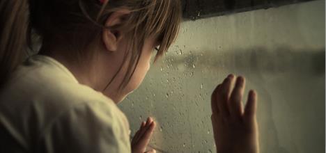girl looking out of a window showing the emotional toll of  child abuse