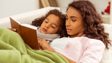 a woman reading a book to a young girl