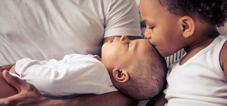 sibling kissing baby's head