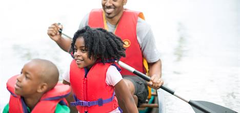 father sister and brother canoe through rapids